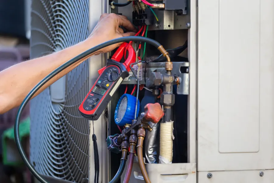 An HVAC technician checking refrigerant line pressure on a residential AC unit