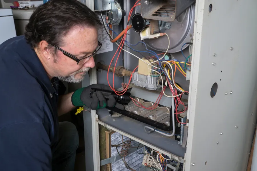 A technician servicing a residential gas furnace