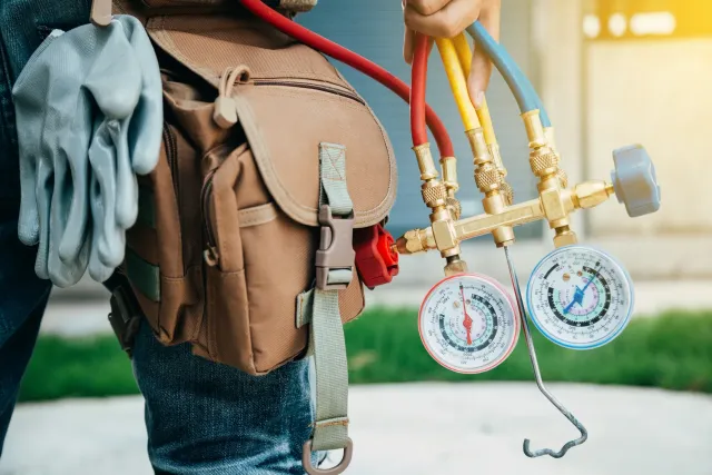An HVAC technician working on the components of a residential air conditioning system
